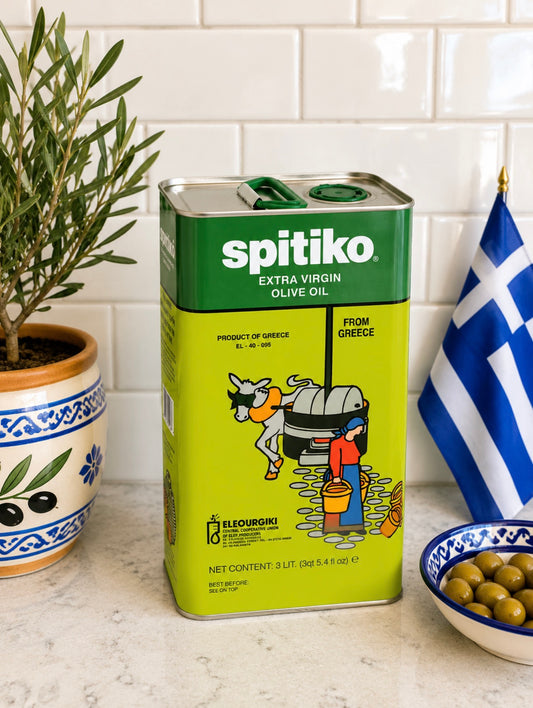 Spitiko olive oil can on a kitchen counter with a Greek flag and olive branch in the background