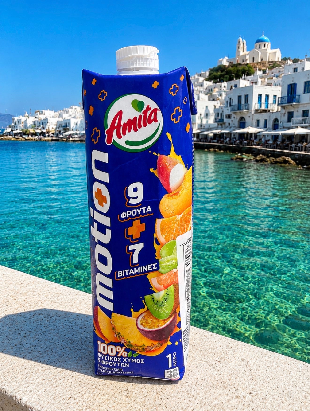 Amita Motion juice box with a scenic background of a coastal town.