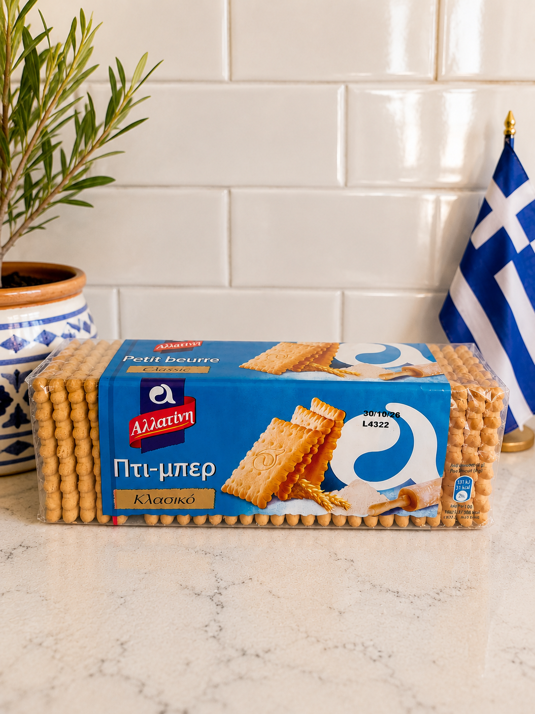 Packaged crackers on a kitchen counter with a plant and Greek flag in the background