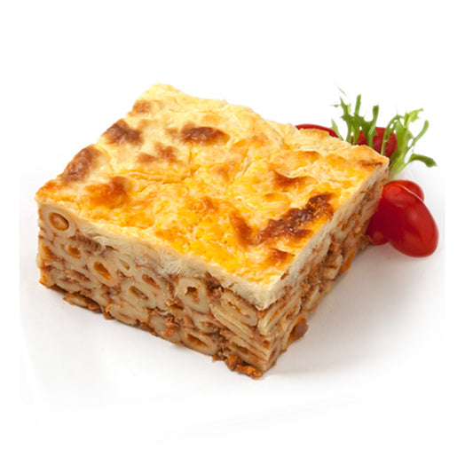 Square piece of baked pasta dish with a tomato and greens on a white background